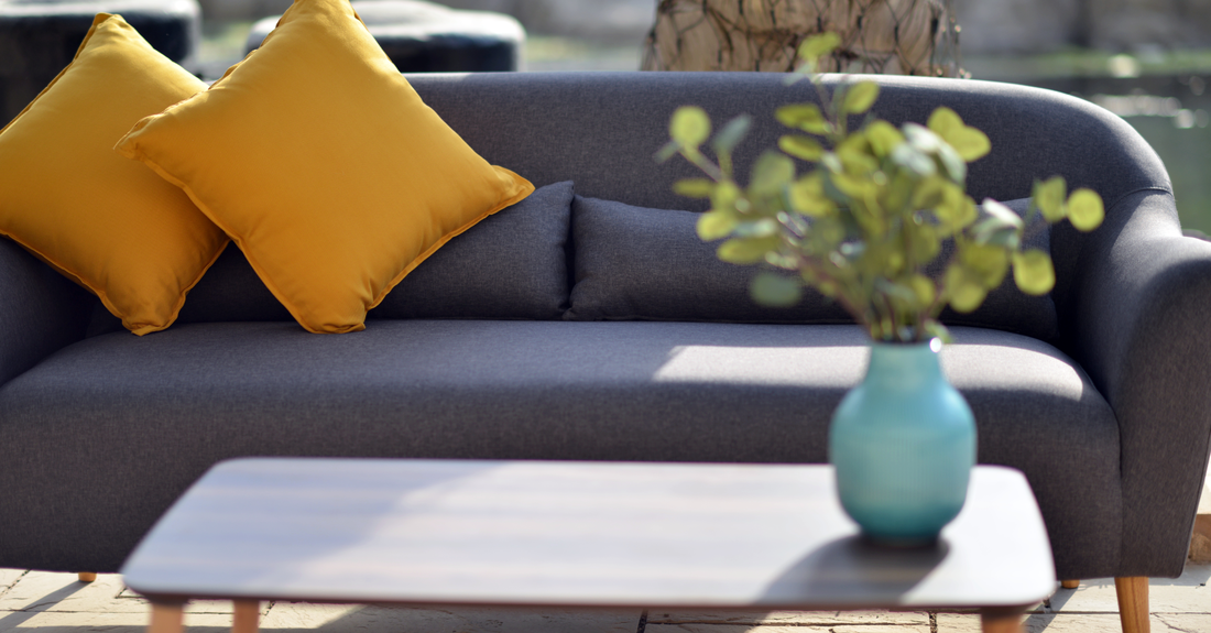 Grey sofa with mustard cushions and blue vase on a coffee table